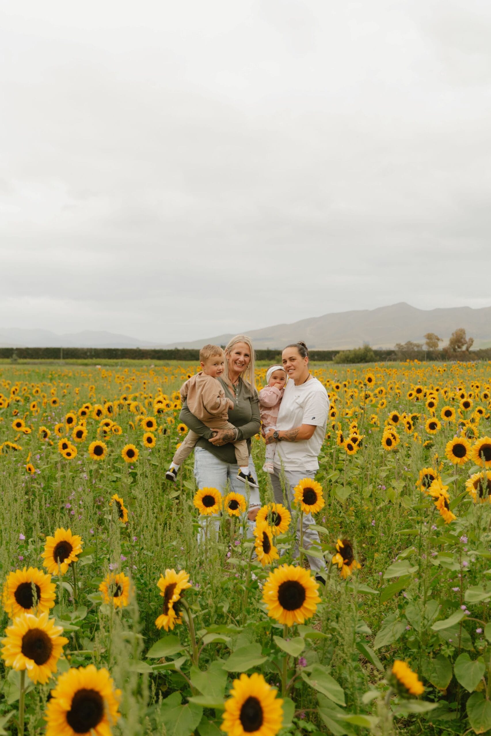 Photo of gorgeous family standing in a sunflower meadow.